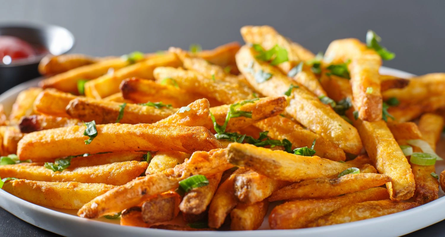 Crispy golden fries garnished with parsley, lime wedges, and red chili slices